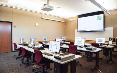 Large screen at the front of a computer room with the HCPL logo projected on it.