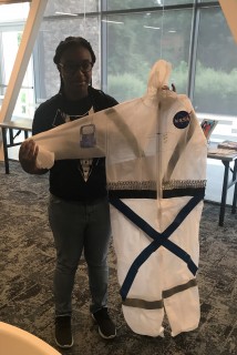 Teen holds up their space suit design.
