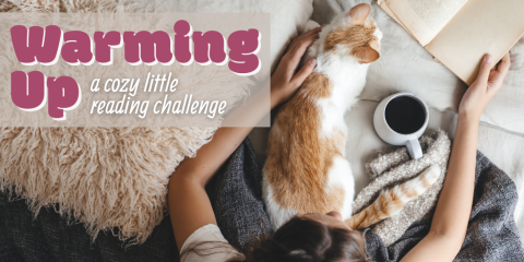 A bird's-eye-view photograph shows someone with dark hair wearing a white t-shirt sitting on a bed under blankets. In front of them is a mug of coffee and a book, and curled up in one of their arms is an orange and white cat. In the upper left corner is dark fuchsia and white text that reads, 