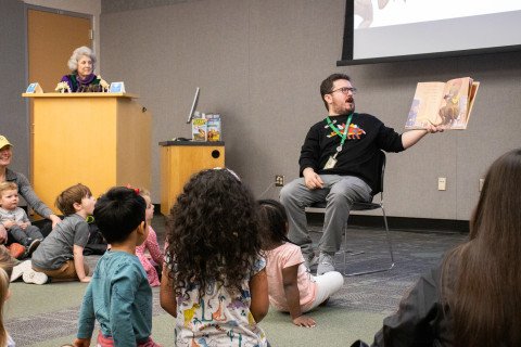 A librarian reads a story about dinosaurs to a room of children.