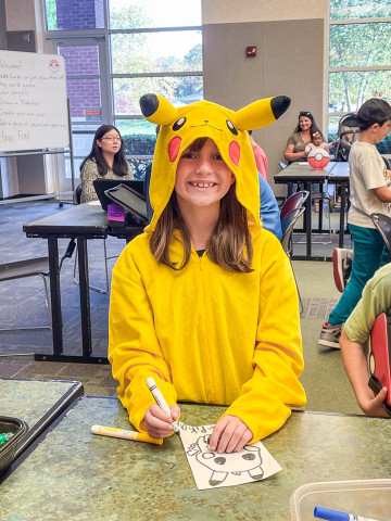 A young girl dressed as Pikachu smiles at the camera.