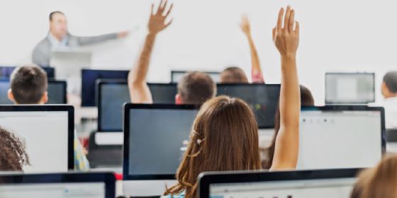 image of students raising their hands in a classroom