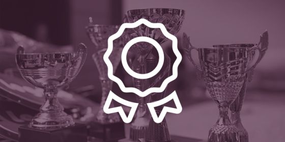 A blue ribbon outline in white over a photo of various sized trophies.