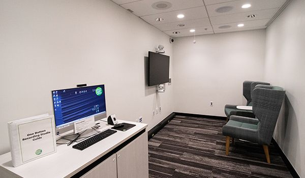 One Button Recording Studio at Fairfield Area Library with cameras, TV screen, two chairs, and computer.